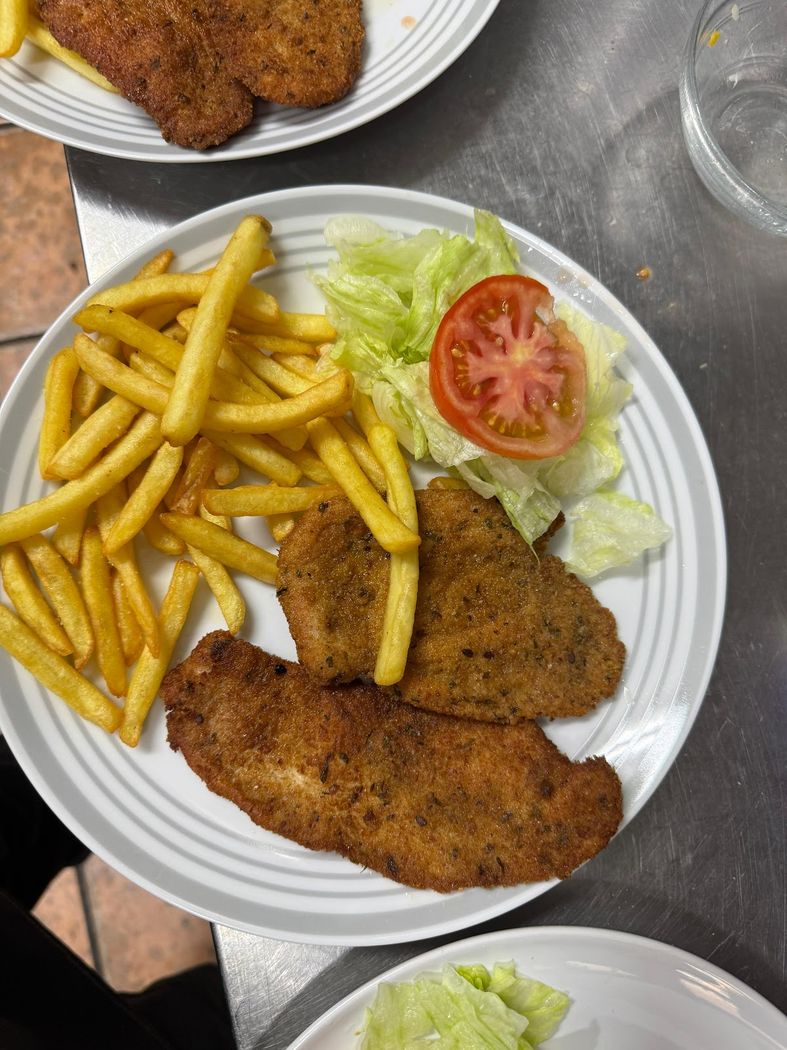 Plato de escalope empanado con patatas fritas y ensalada.