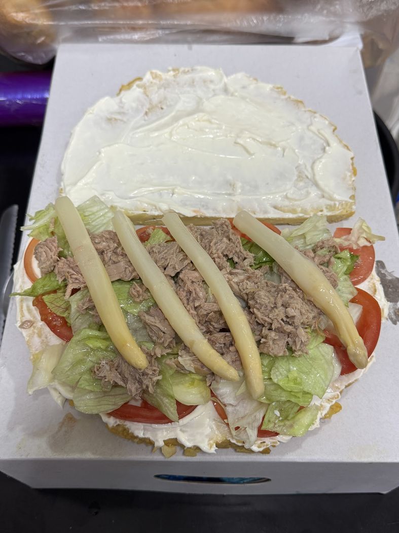 Sándwich abierto de atún con espárragos y verduras frescas.